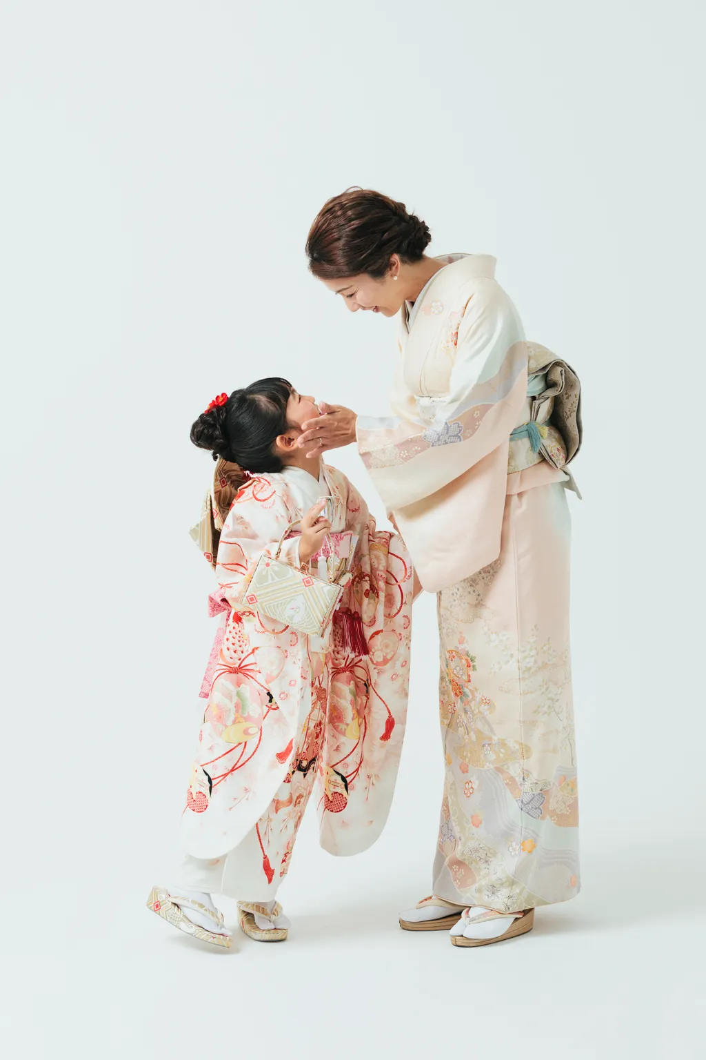 着付けを終えた着物姿の母娘。母親が娘の身支度を整える様子